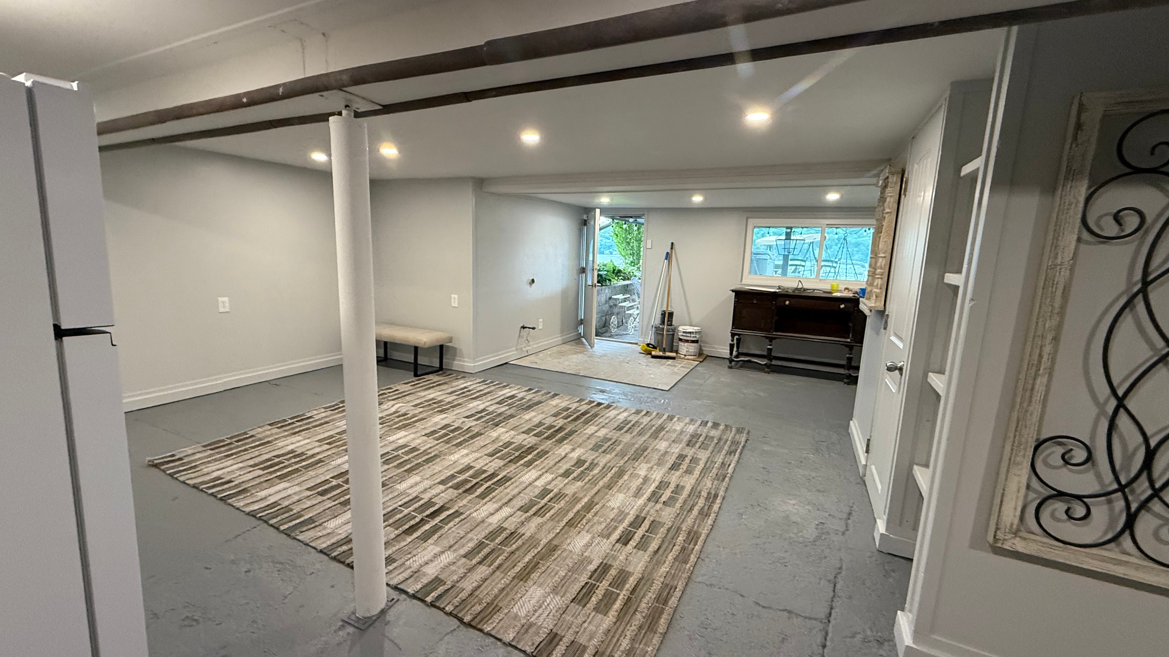 Large open basement room with a patterned rug and gray concrete flooring in Ontario, NY