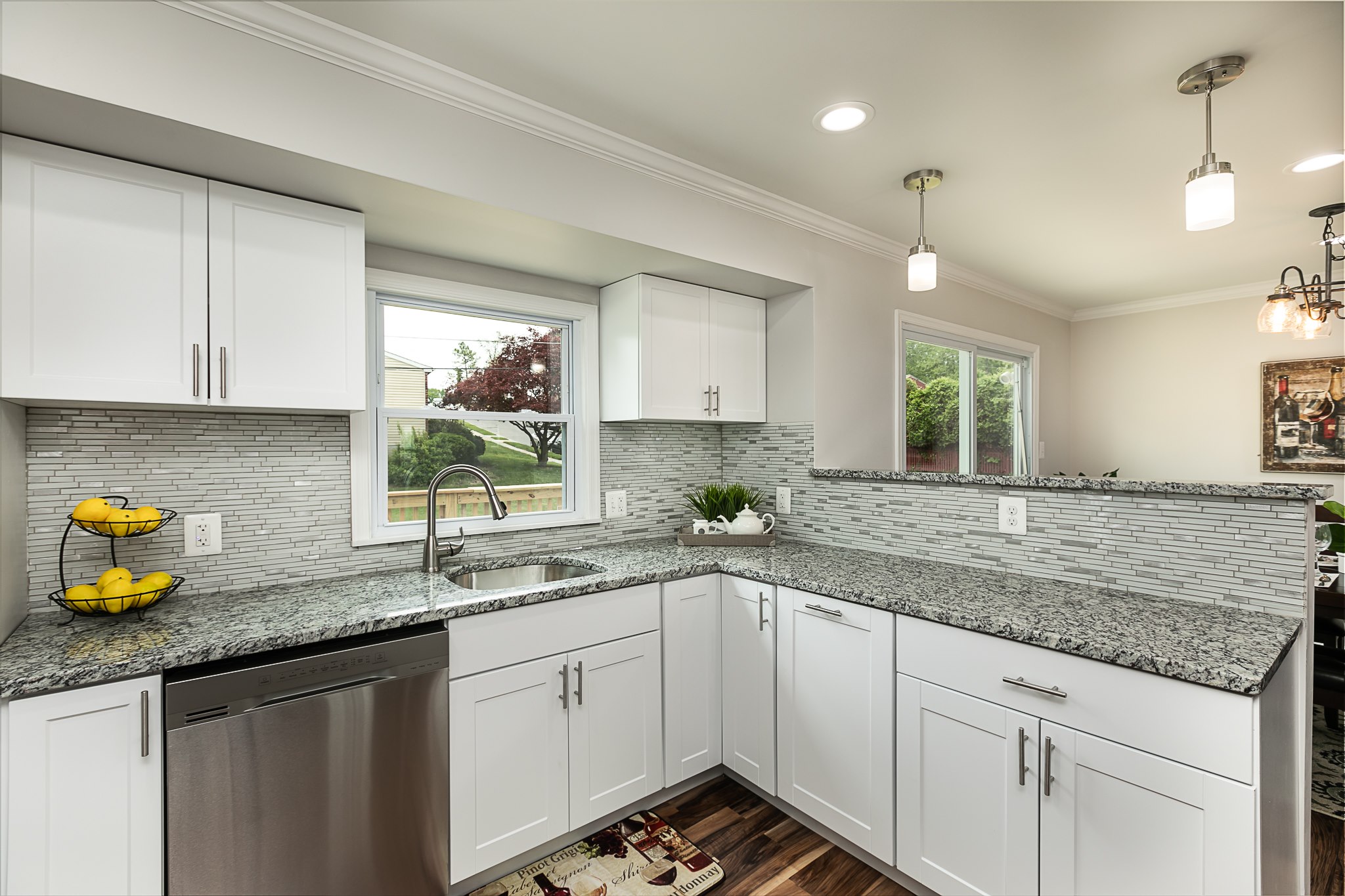 Kitchen corner featuring white cabinets, granite counters, and gray tile backsplash