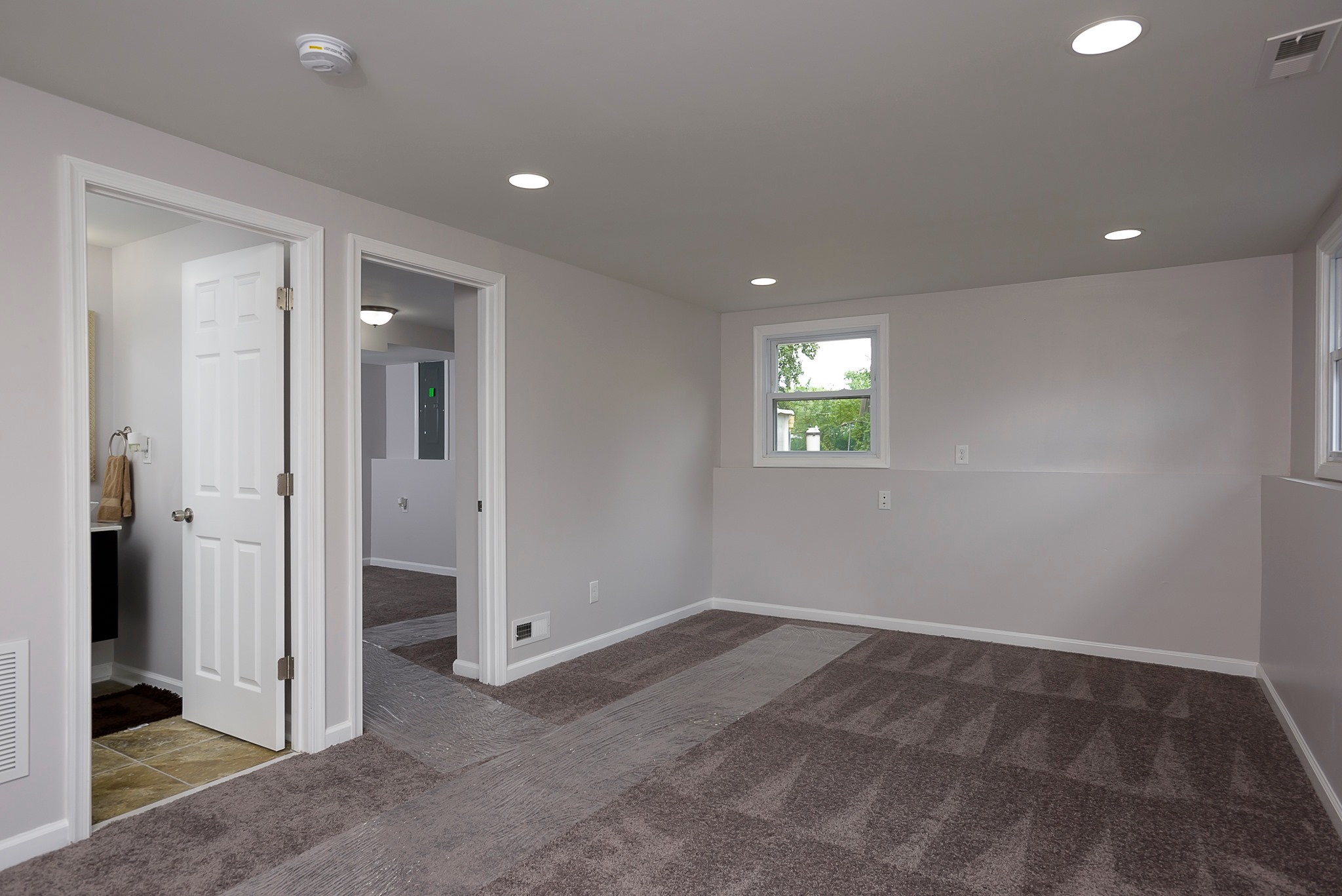 Basement room with gray carpet and white trim around walls in Lyons, NY