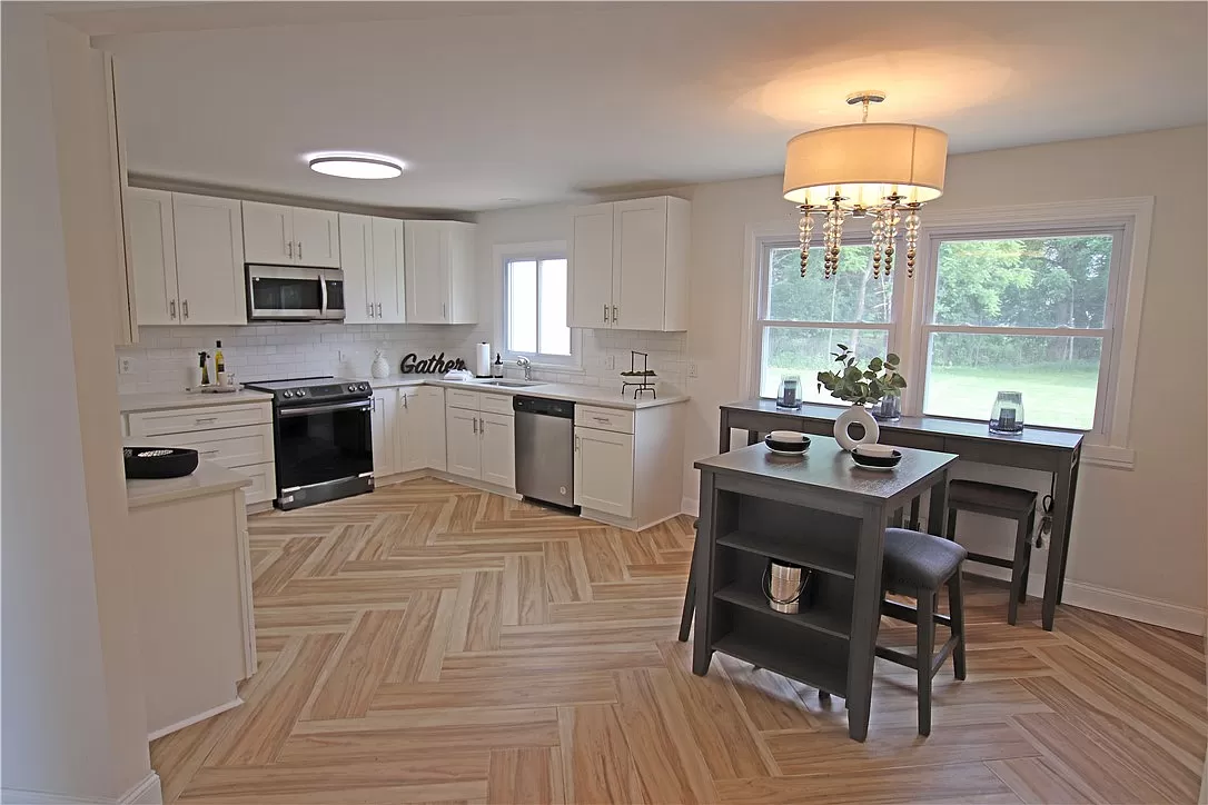Kitchen with white cabinets, herringbone wood floor and small dining table in Hannibal, NY