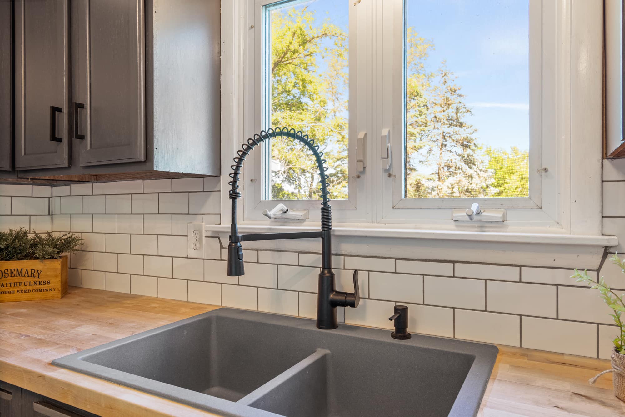 Double kitchen sink with a high-neck faucet in front of window