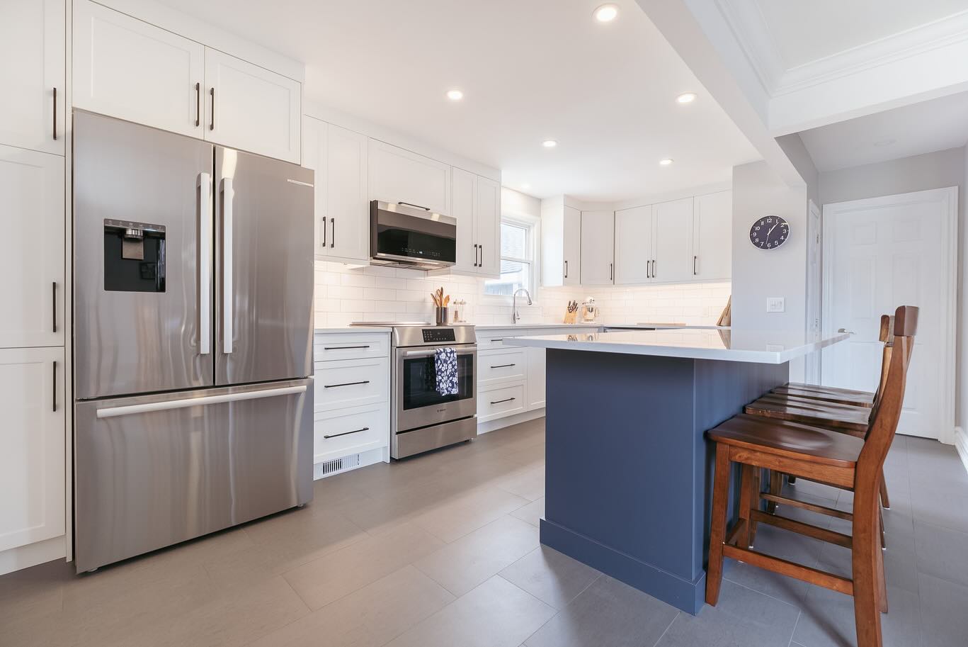 Kitchen with white wall cabinets, blue island, and light wood flooring in Clyde, NY