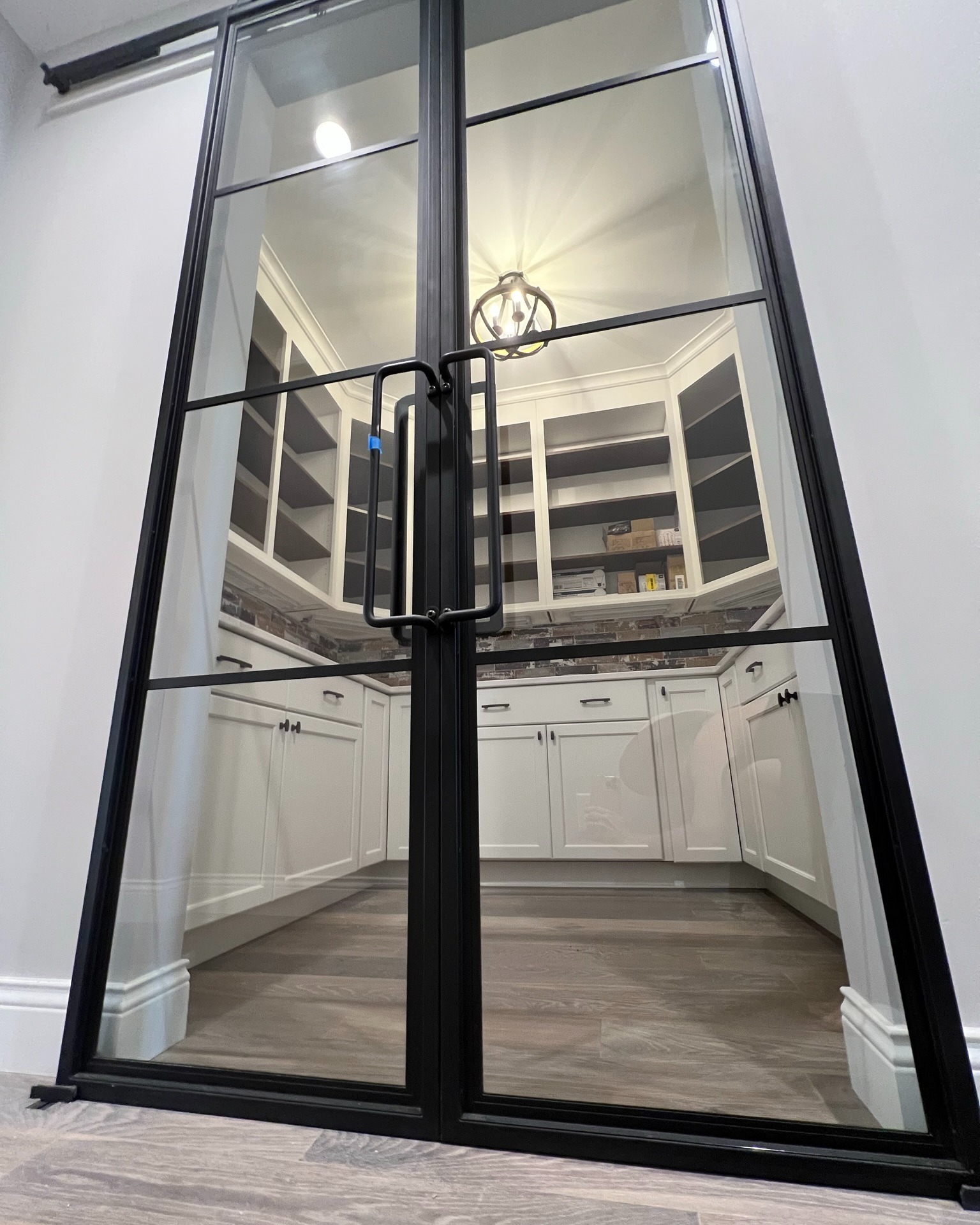 Black-framed glass double doors leading into a white kitchen with visible cabinetry in Cato, NY