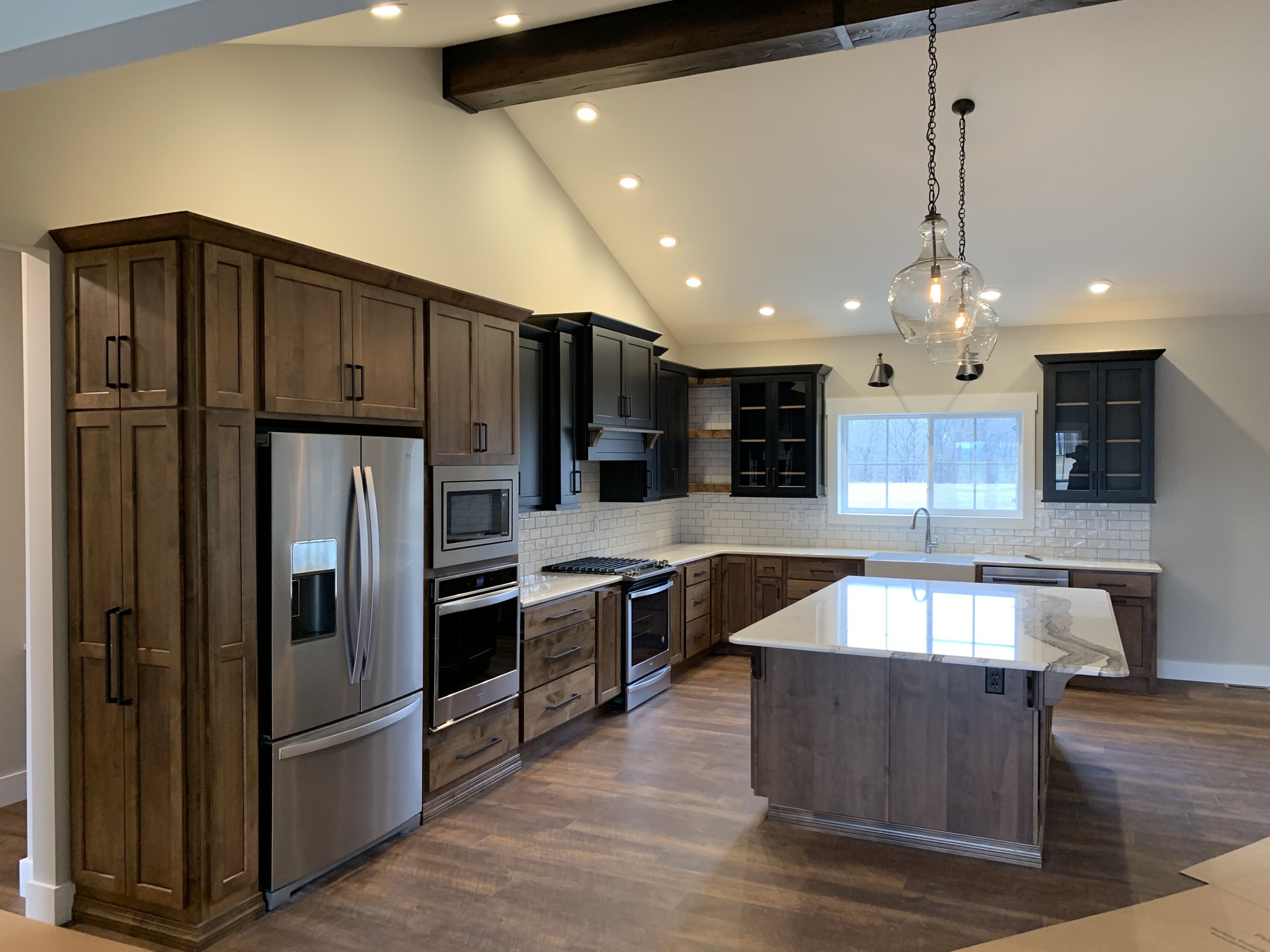 Kitchen with dark cabinetry, stainless appliances, and wooden flooring throughout in Wayne County, NY