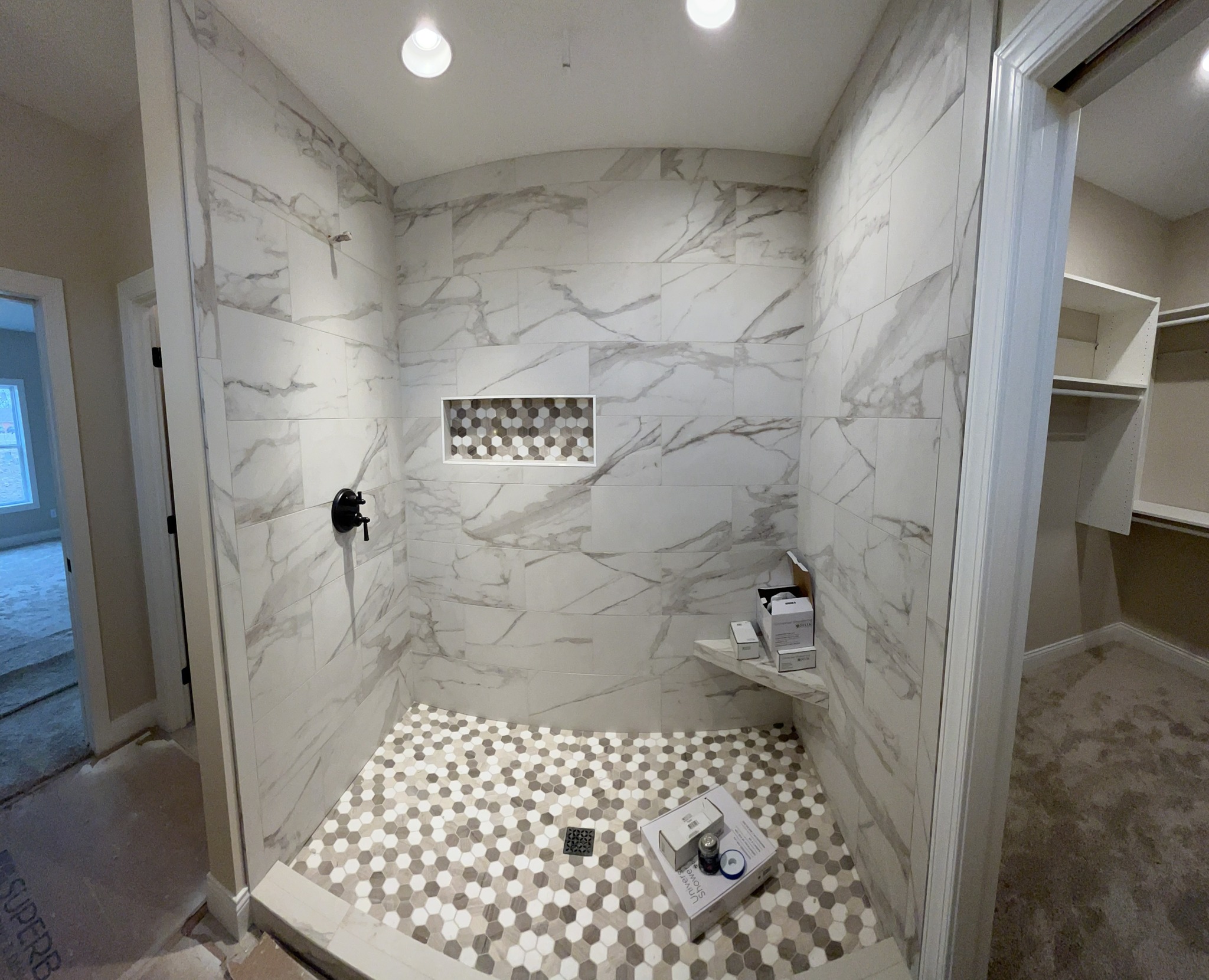 Walk in shower with large marble tile and hexagonal floor tiles in Oswego, NY