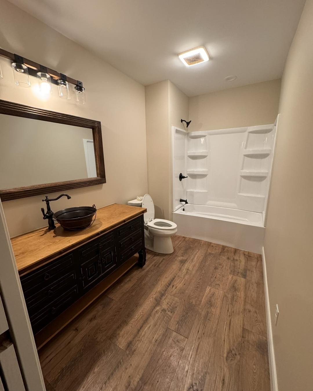 Bathroom with dark wood vanity, copper vessel sink and tub shower