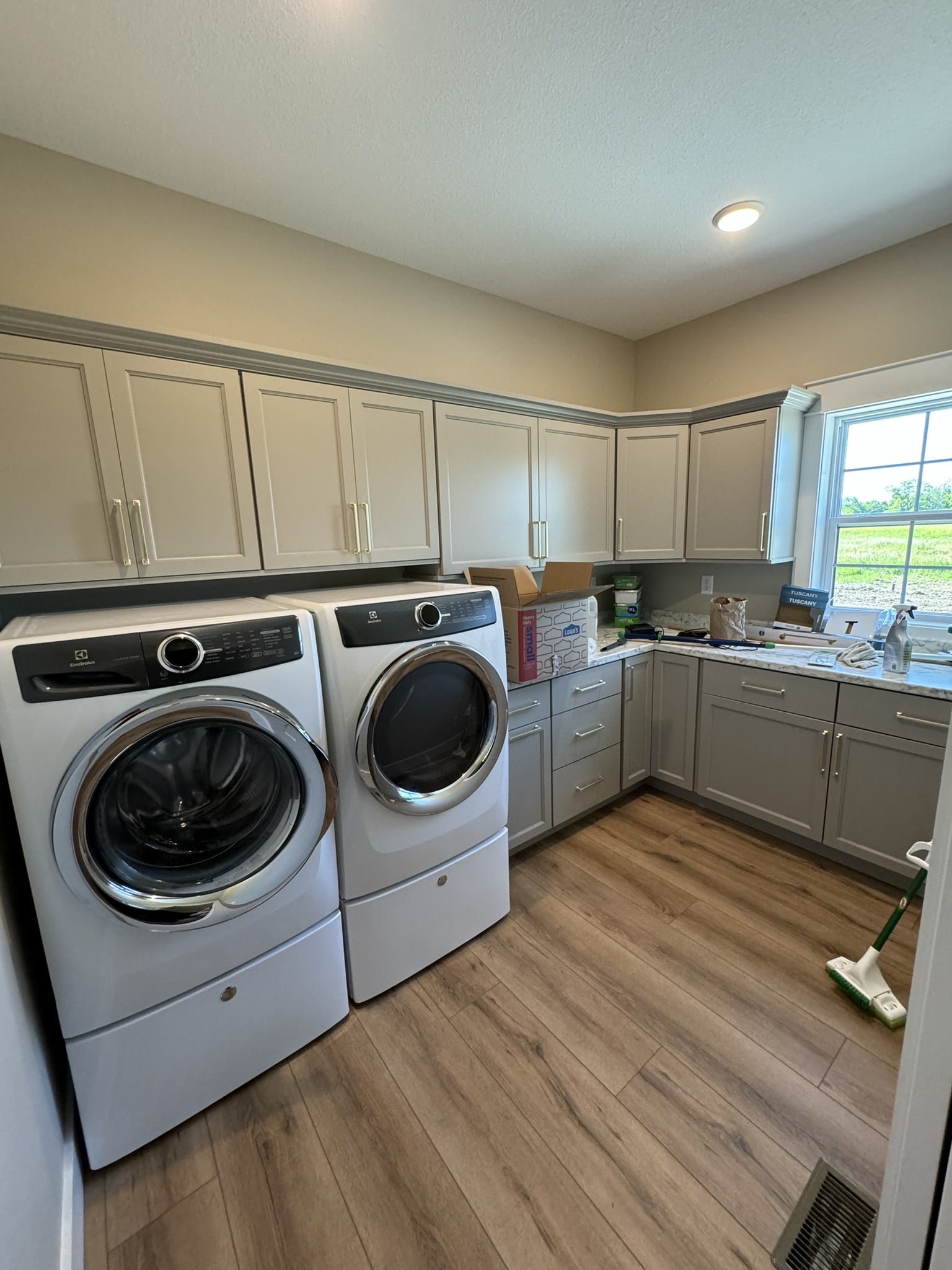 Laundry room with white stacked washer and dryer and gray cabinets in Williamson, NY