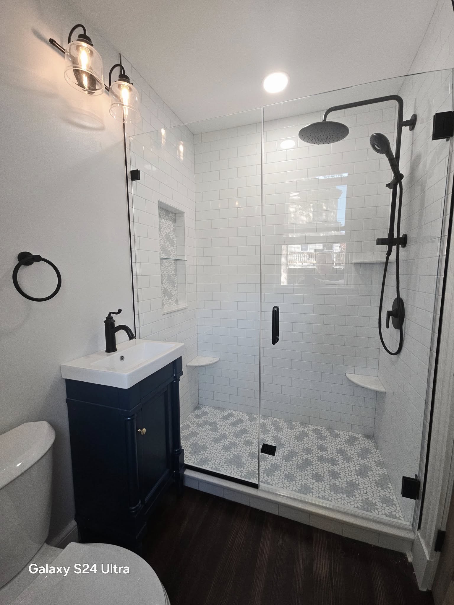 Bathroom shower with white subway tiles, glass door, and dark vanity cabinet in Cato, NY