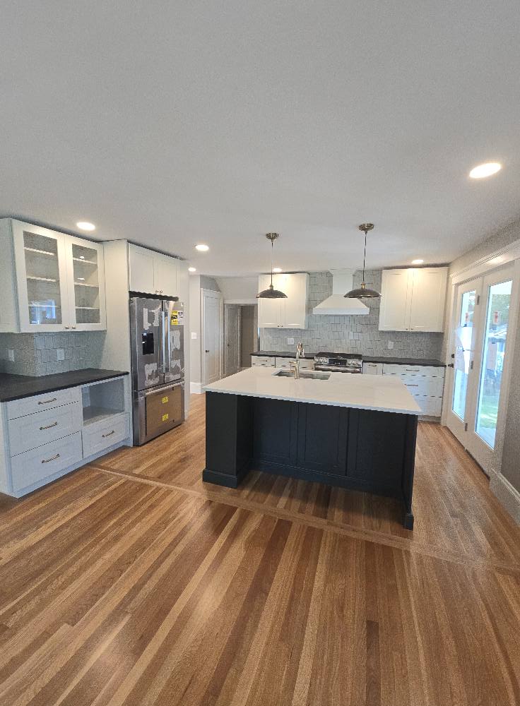 Modern kitchen with center island, white cabinets, and wood plank flooring in Baldwinsville, NY