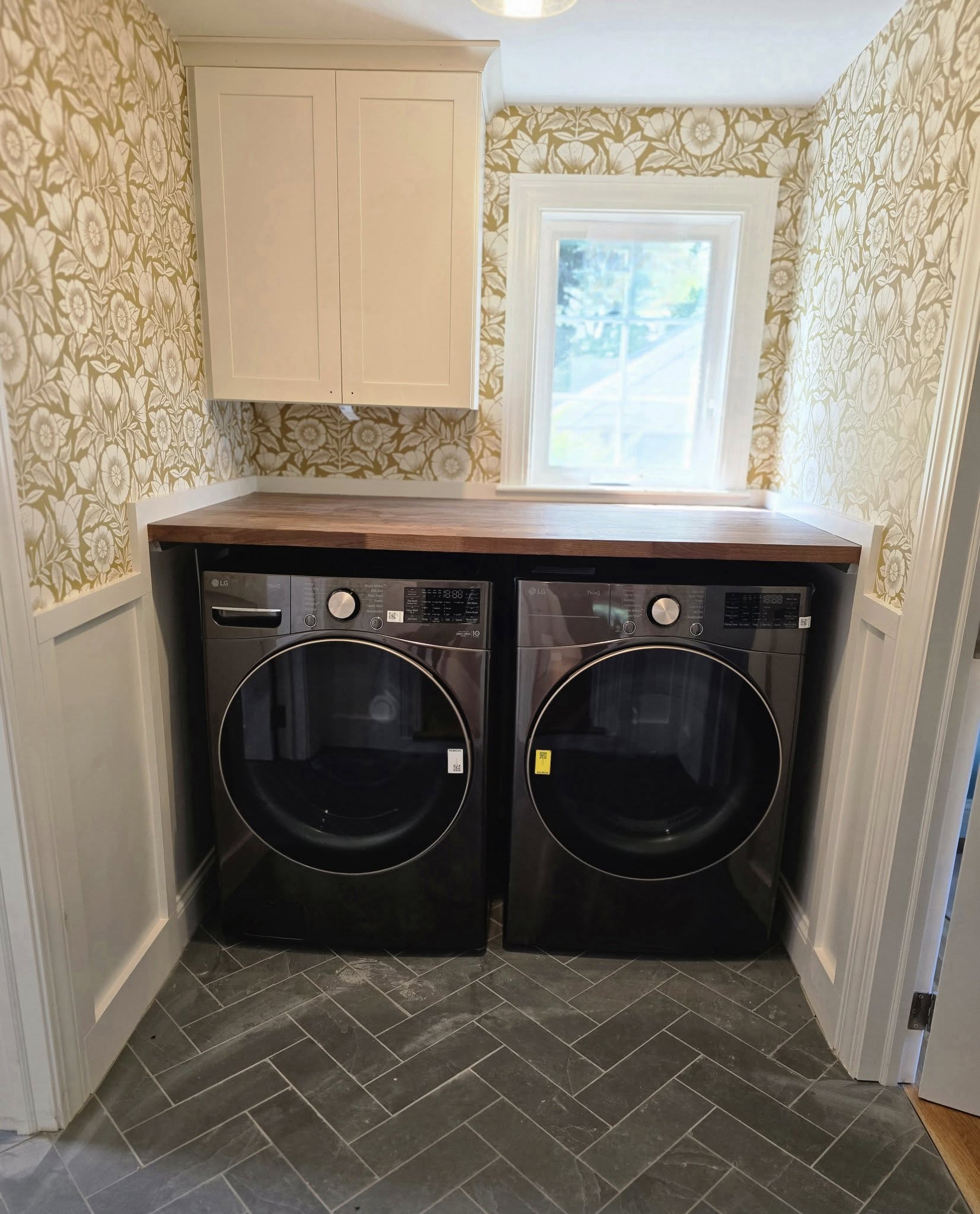 Laundry room with patterned wallpaper wooden countertop and two front load machines in Red Creek, NY
