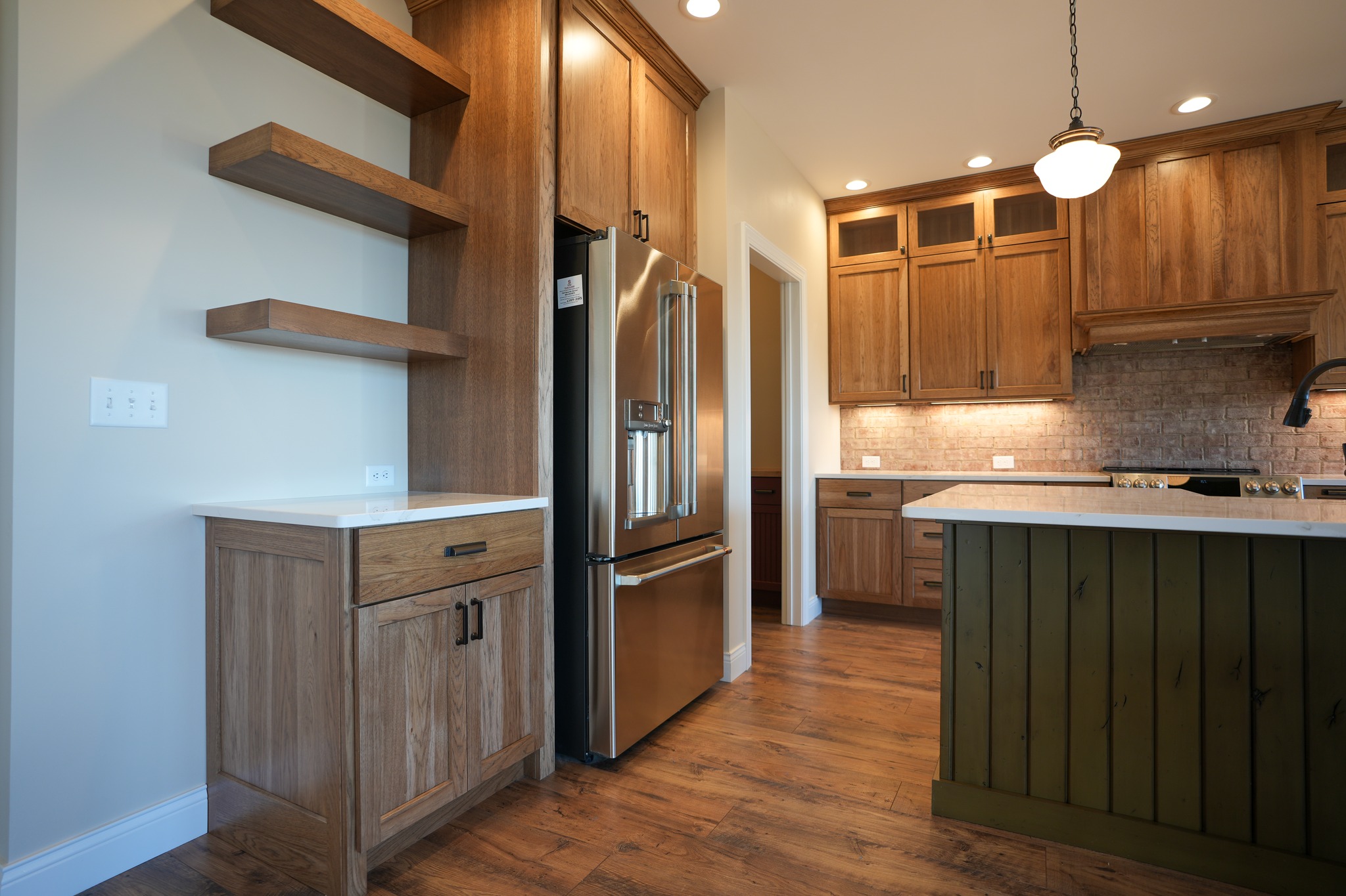 Kitchen with wooden cabinets, floating shelves, and a green island base in Oswego, NY