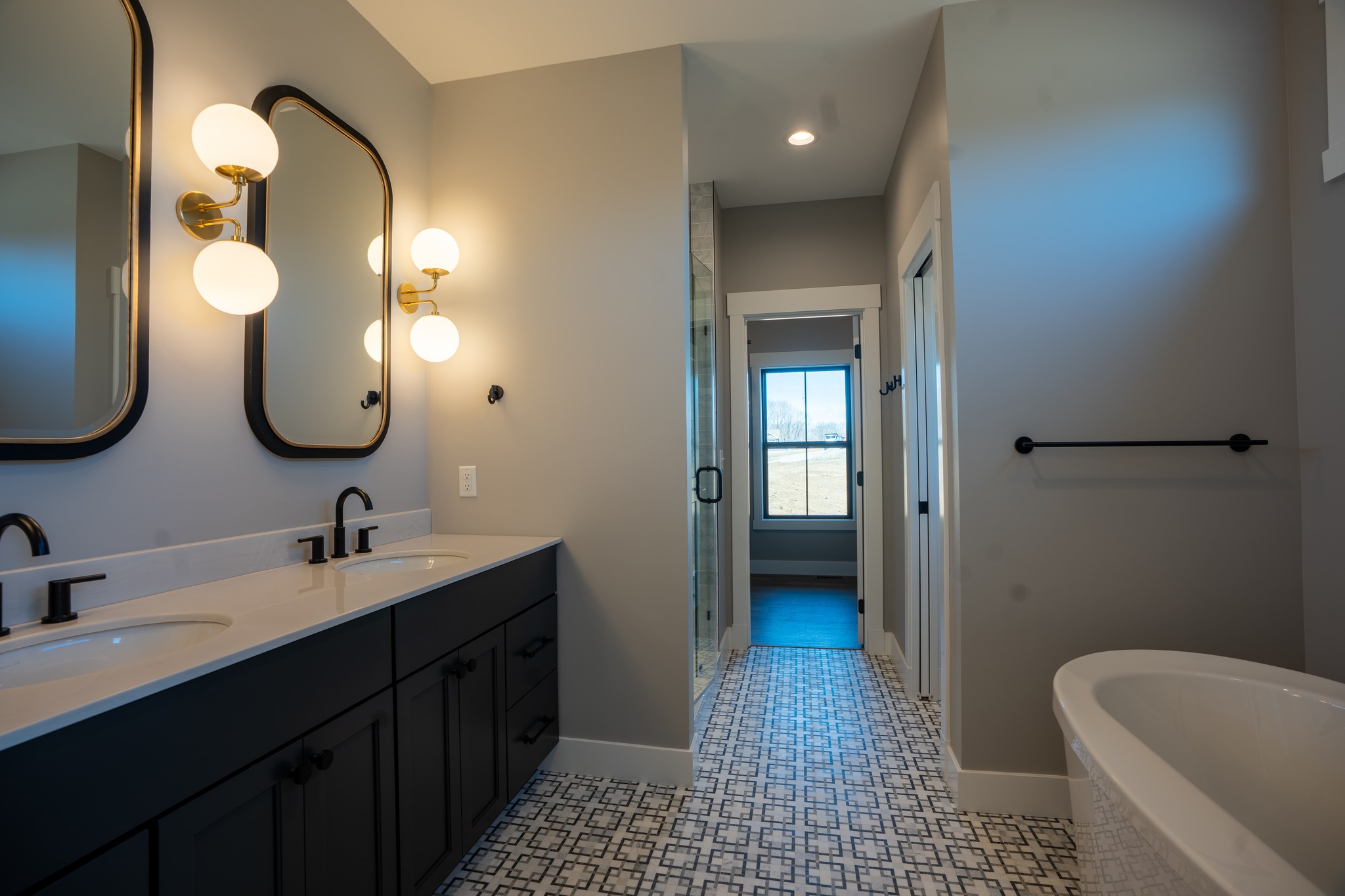 Bathroom with dual vanity, black cabinets and geometric floor tile