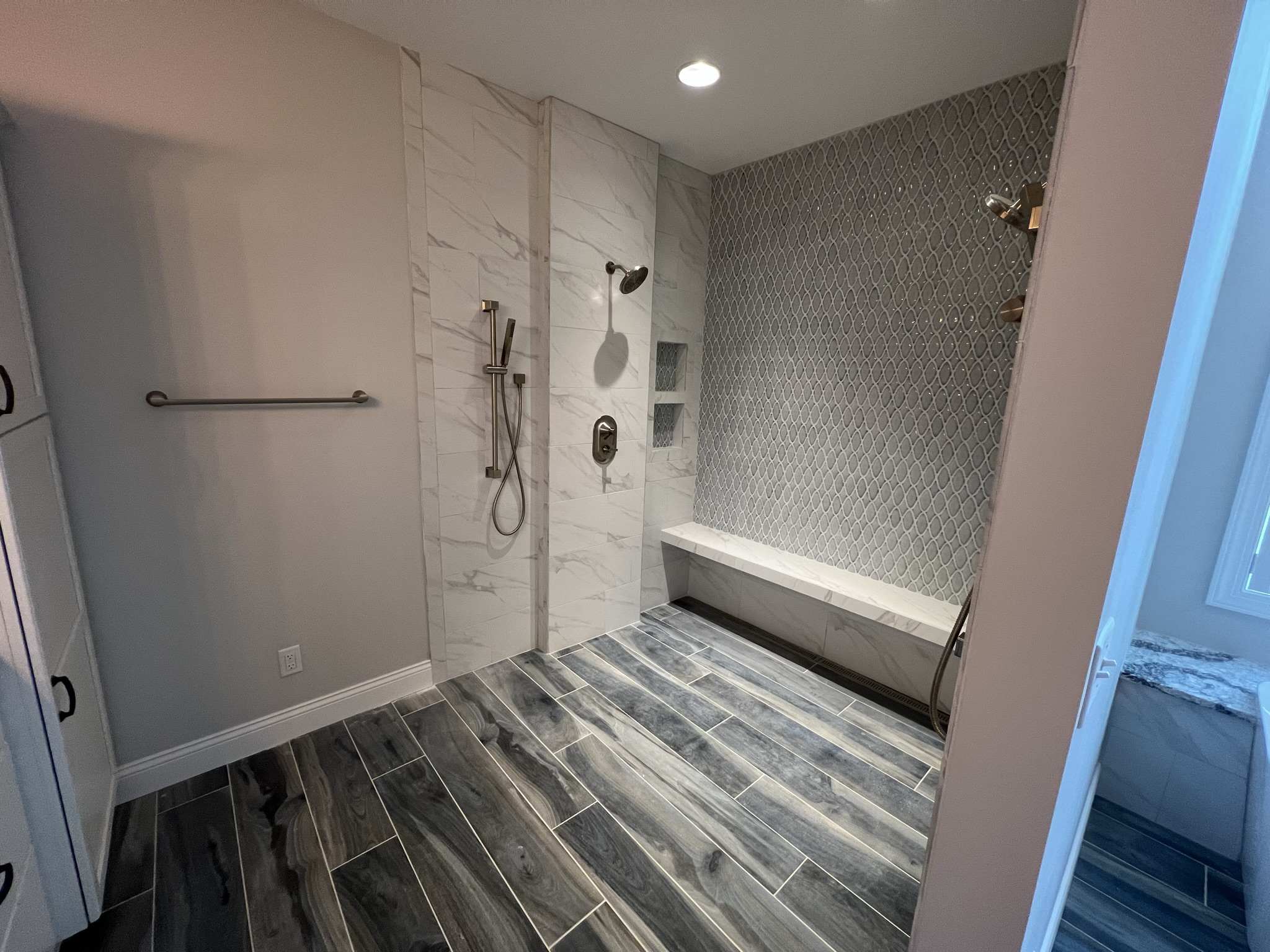 Bathroom with walk in shower featuring built in bench and dark tile in Wolcott, NY