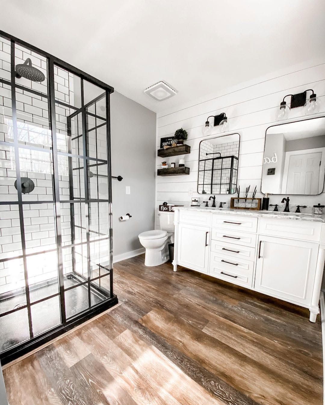 Bathroom with a black-framed glass shower, white vanity, and shiplap walls in Phoenix, NY
