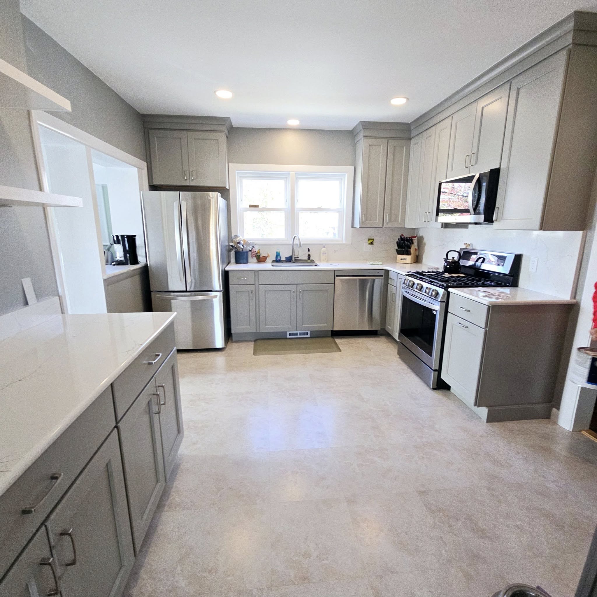 Kitchen with light gray cabinets stainless steel refrigerator and light tile flooring in Savannah, NY