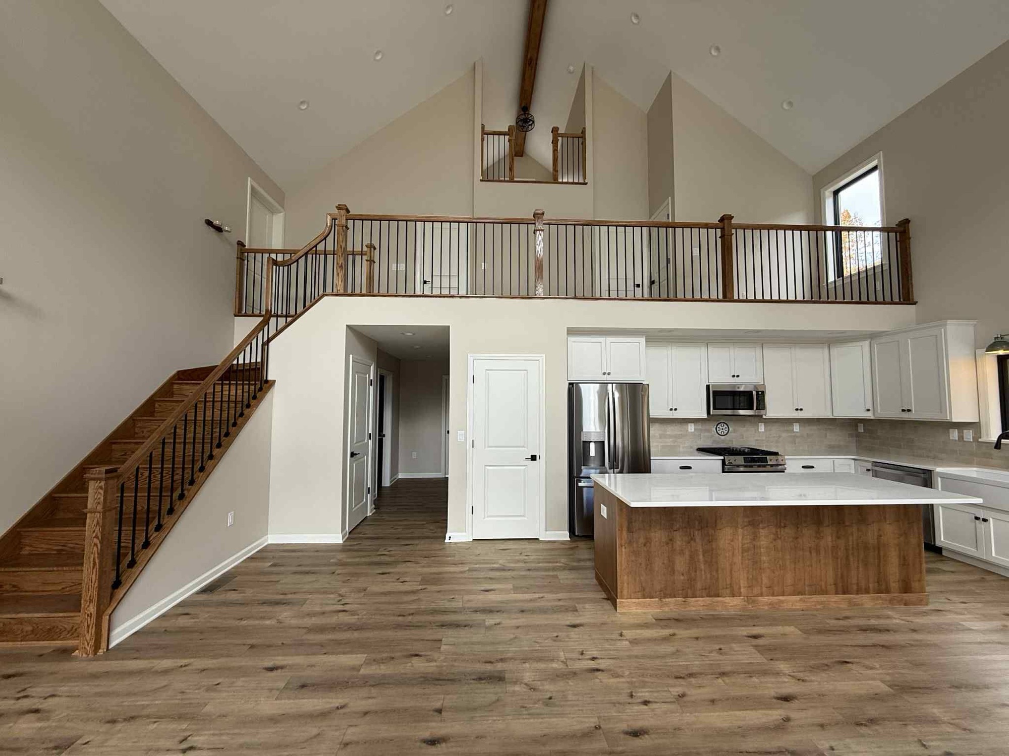 Open living area with staircase kitchen island and loft balcony looking down in Fulton, NY