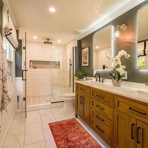 Modern bathroom with a wooden vanity, glass shower, and white tile floor in Cato, NY