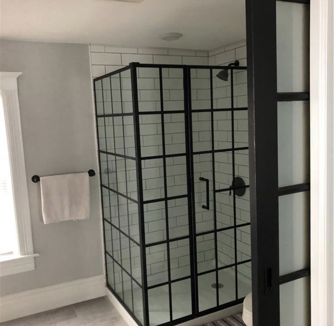 Bathroom shower with white subway tiles and a black framed glass enclosure in Marion, NY