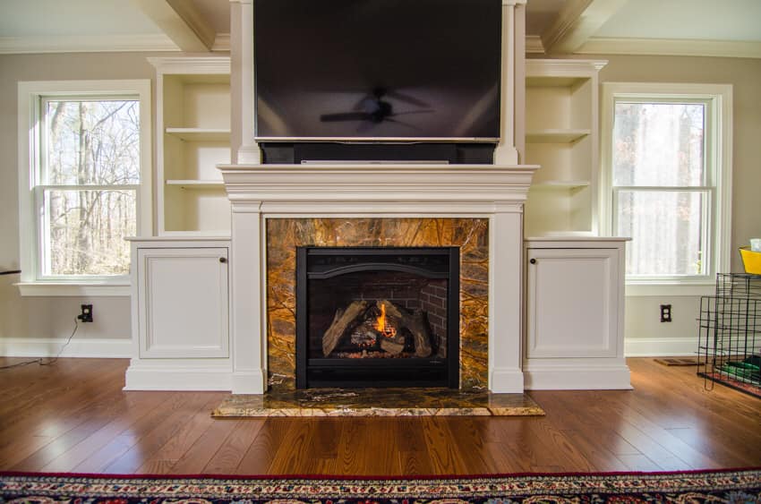 Stone fireplace with a white mantel and built-in bookshelves on both sides in North Rose, NY