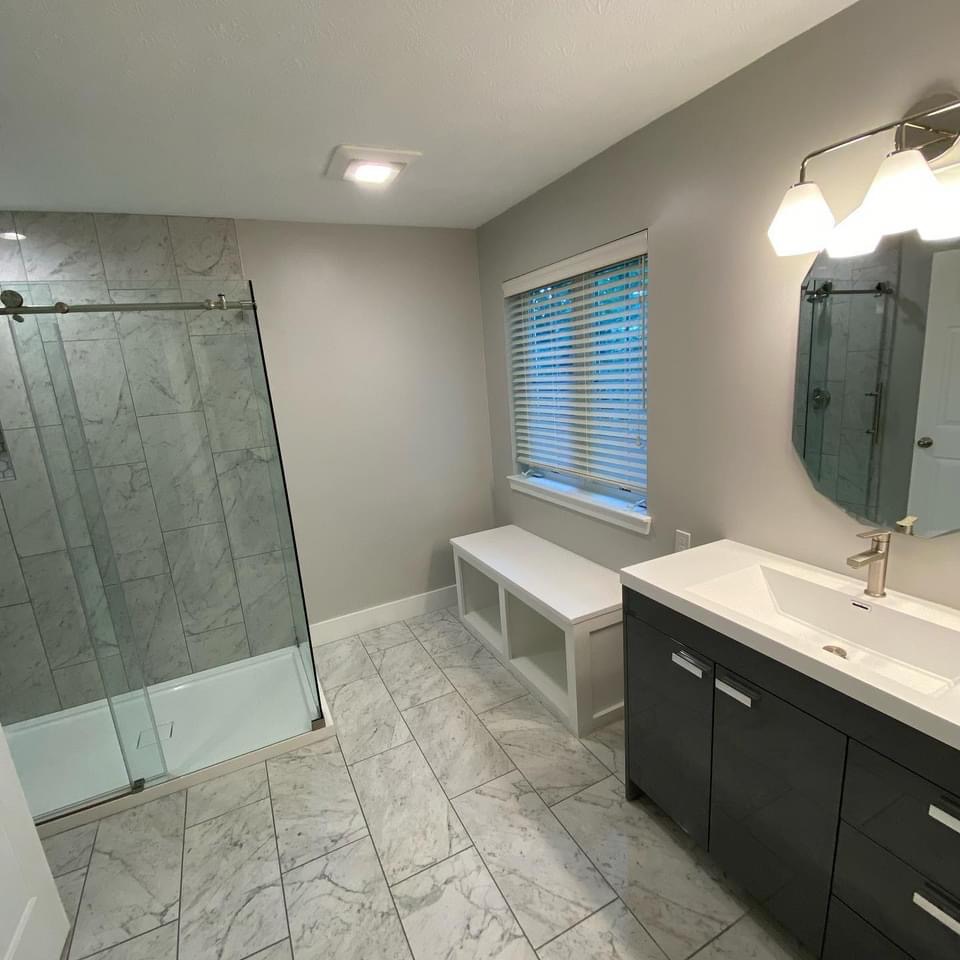 Bathroom renovation with marble tile flooring and glass shower enclosure in Clyde, NY