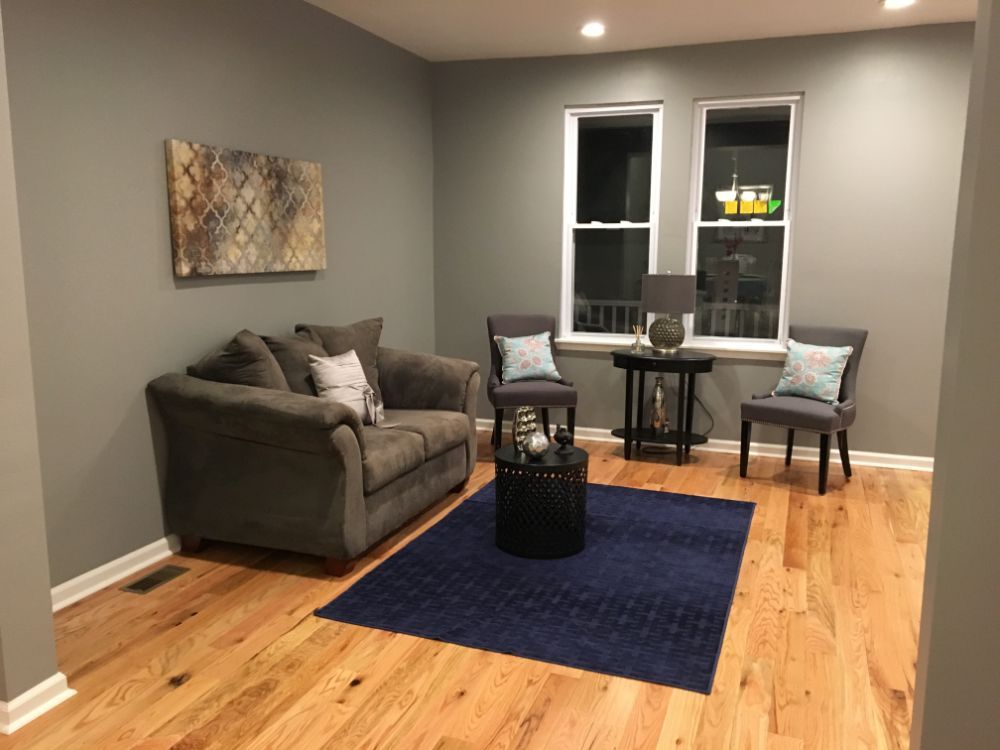 Living room with hardwood floors, gray walls and blue area rug in Macedon, NY