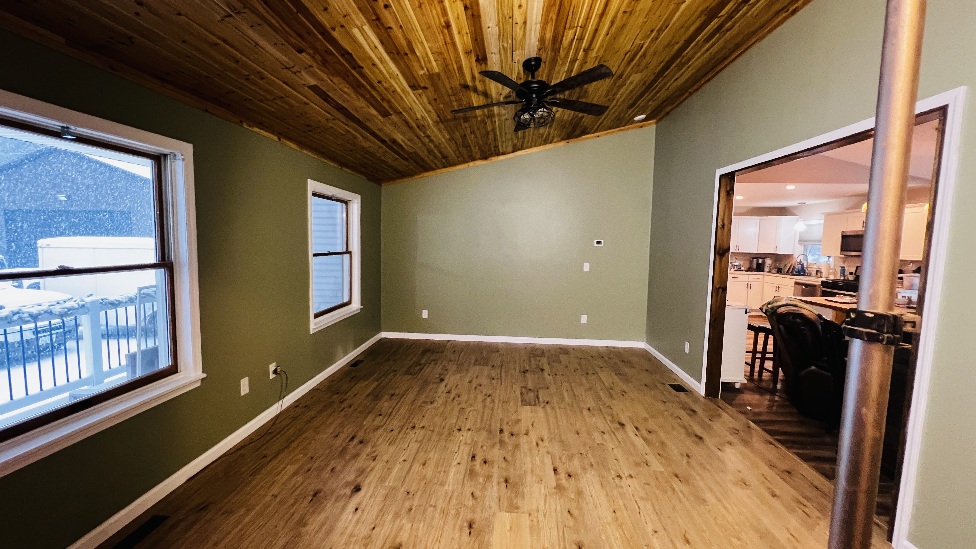 Room with light flooring, sage green walls, and a wooden ceiling