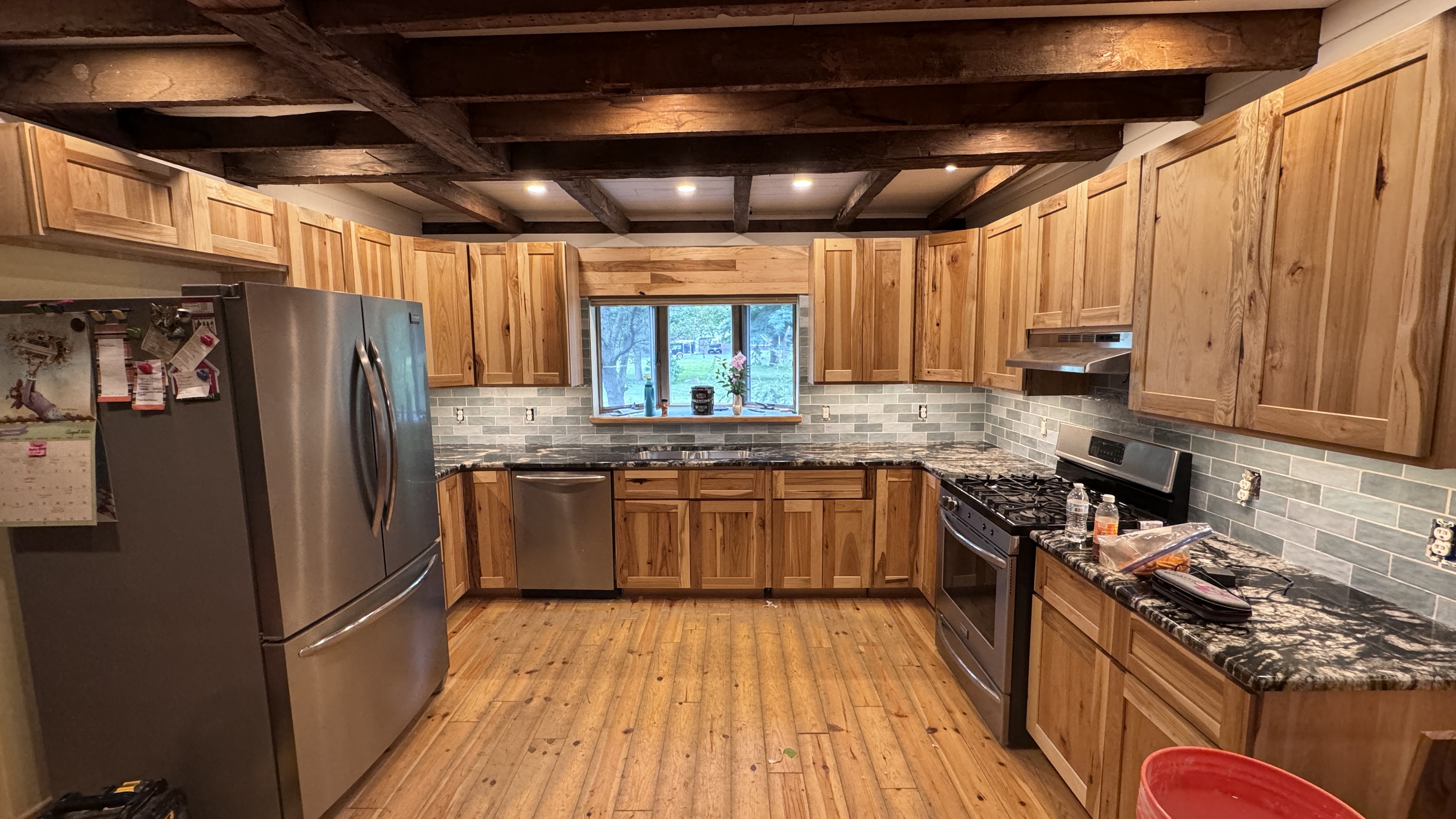Kitchen with natural wood cabinets, stainless appliances, and exposed wooden ceiling beams