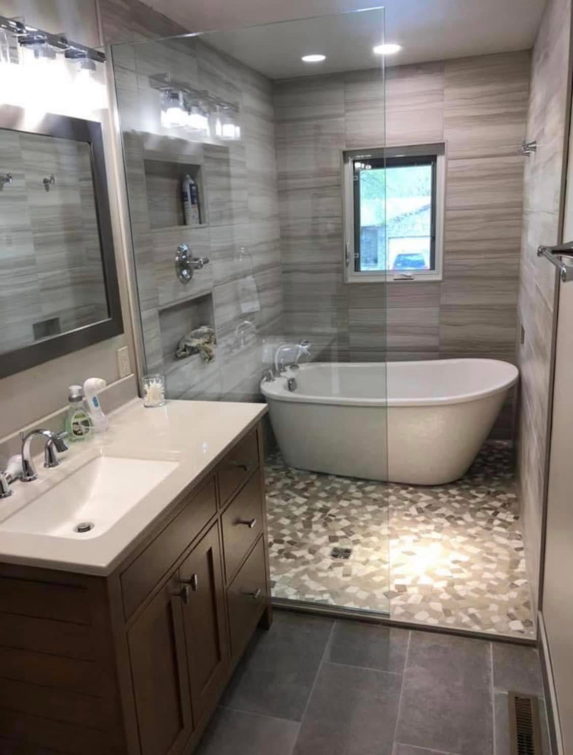 Bathroom with wooden double vanity freestanding tub and stone tile shower area