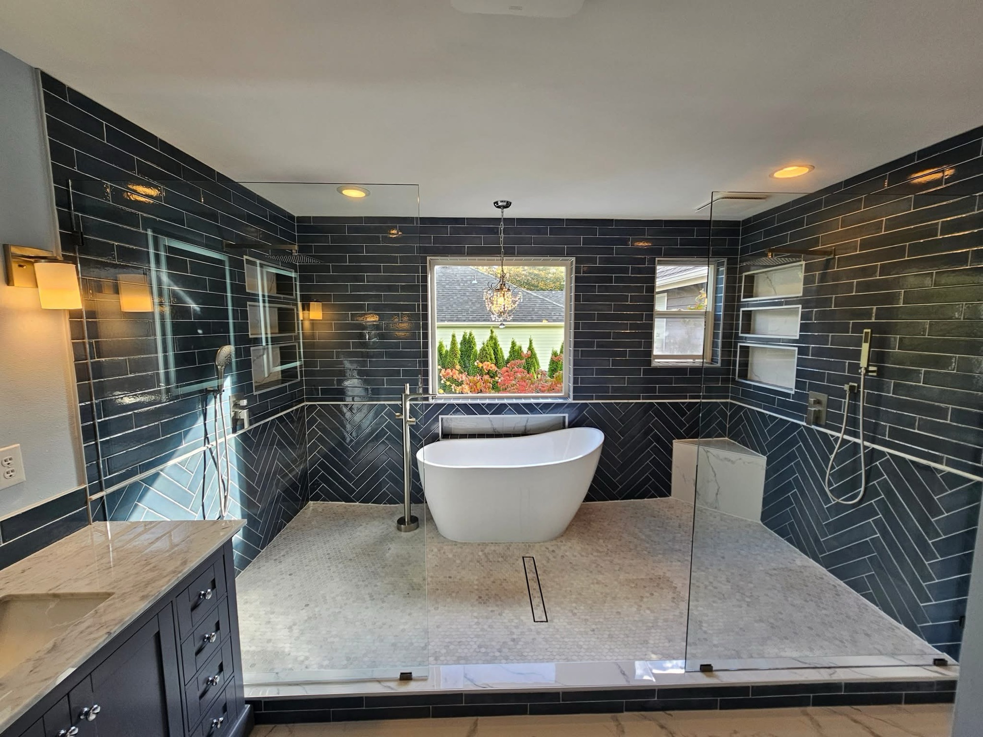 Large glass walk-in shower area with freestanding tub and dark tile accents in Marion, NY